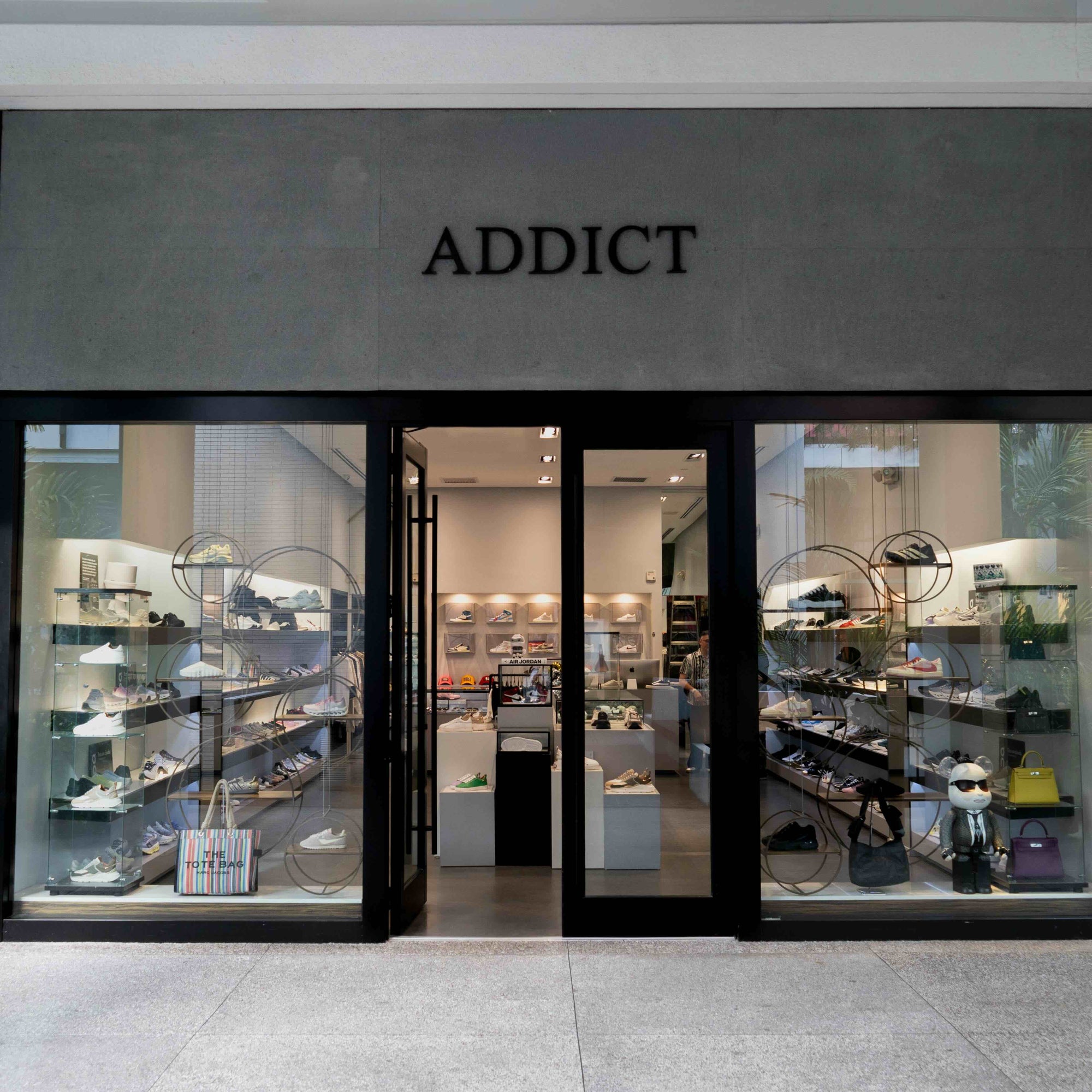 The ADDICT storefront at Bal Harbour Shops, glass windows lined with sneakers and handbags